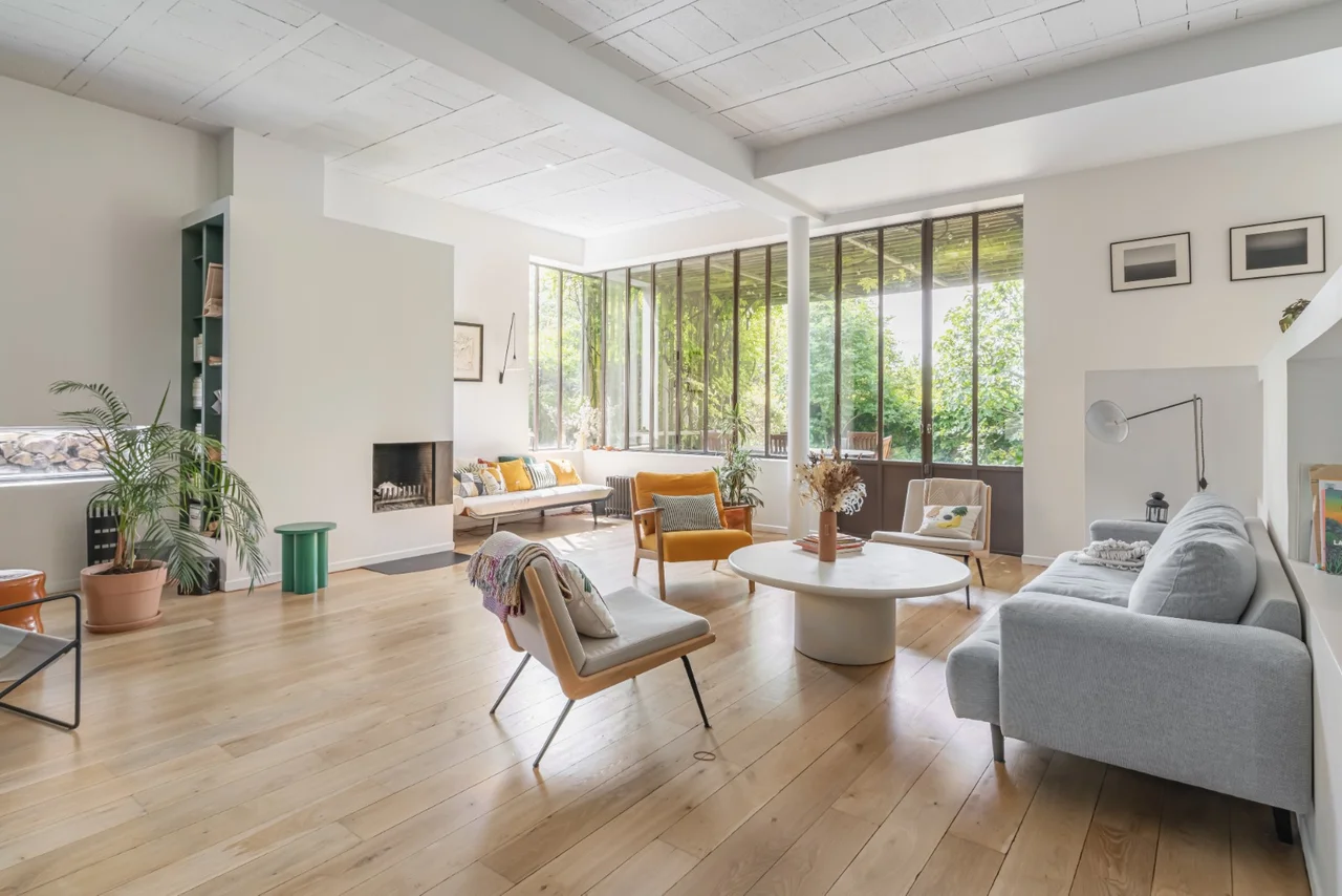 Grand salon lumineux avec cheminée et baies vitrées donnant sur le jardin
