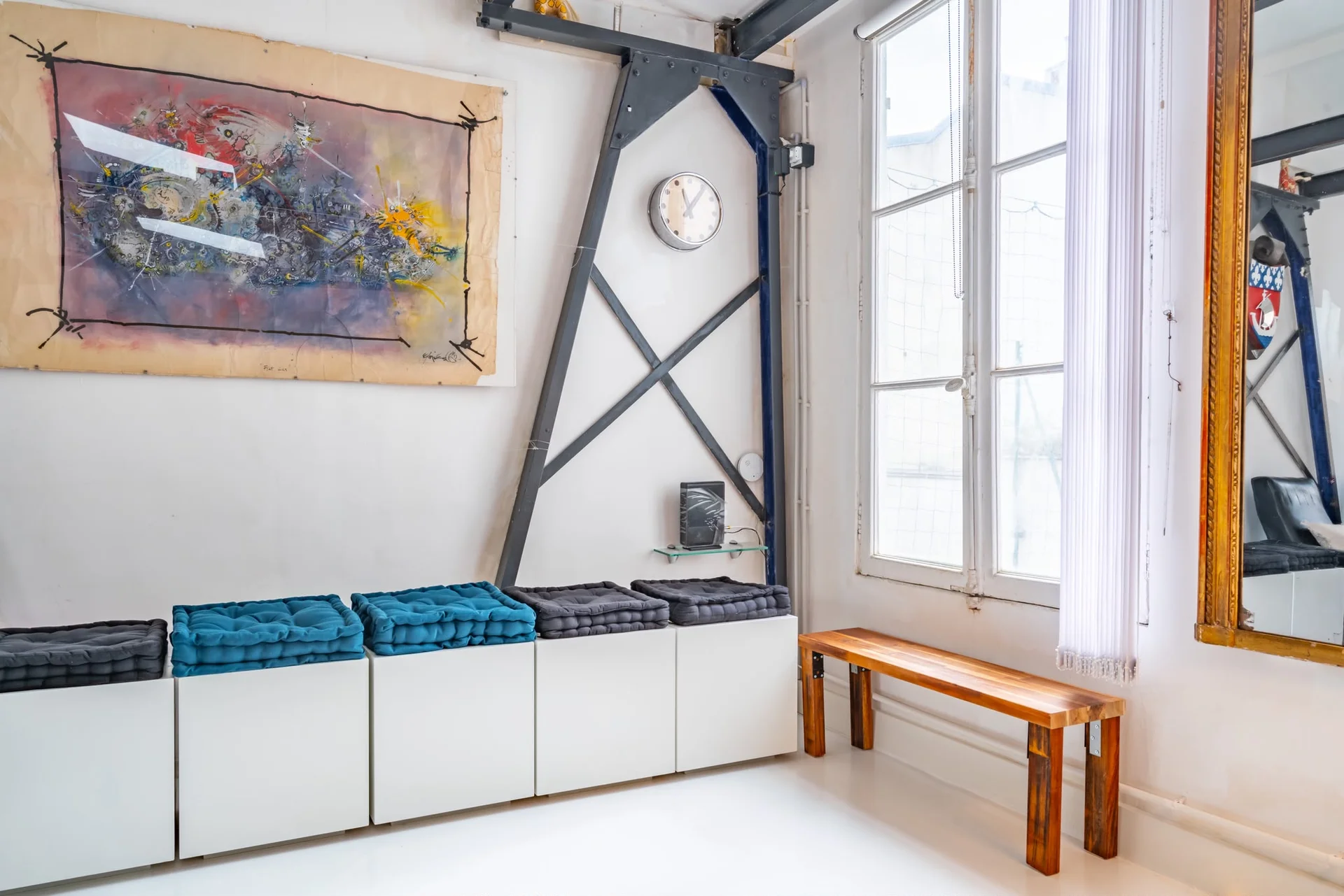 Espace détente du loft industriel à Paris avec banquette, coussins et œuvre contemporaine