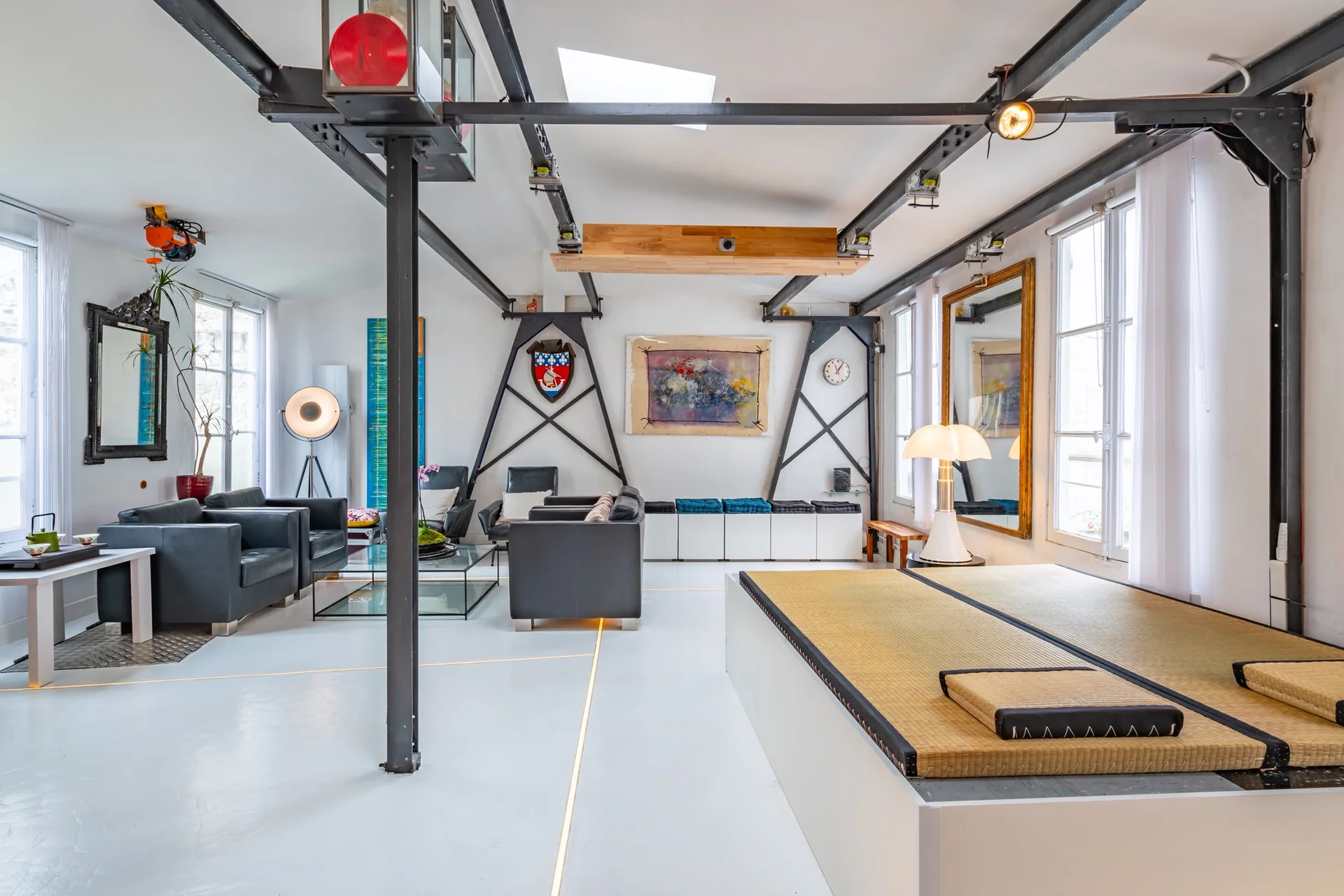 Grand espace modulable du loft parisien avec salon, plateforme et poutres métalliques