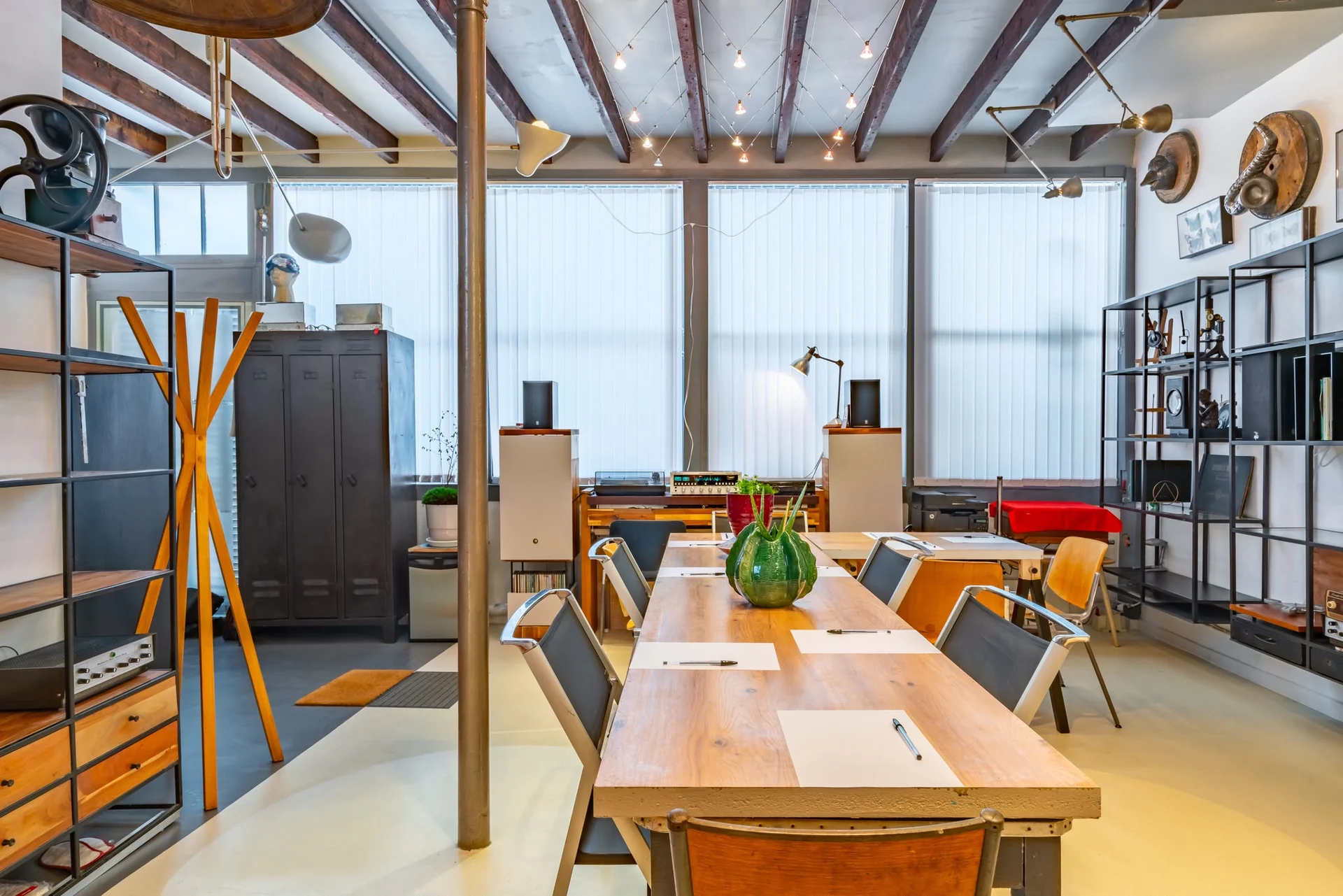 Espace réunion du loft parisien avec grande table en bois, chaises et décoration industrielle