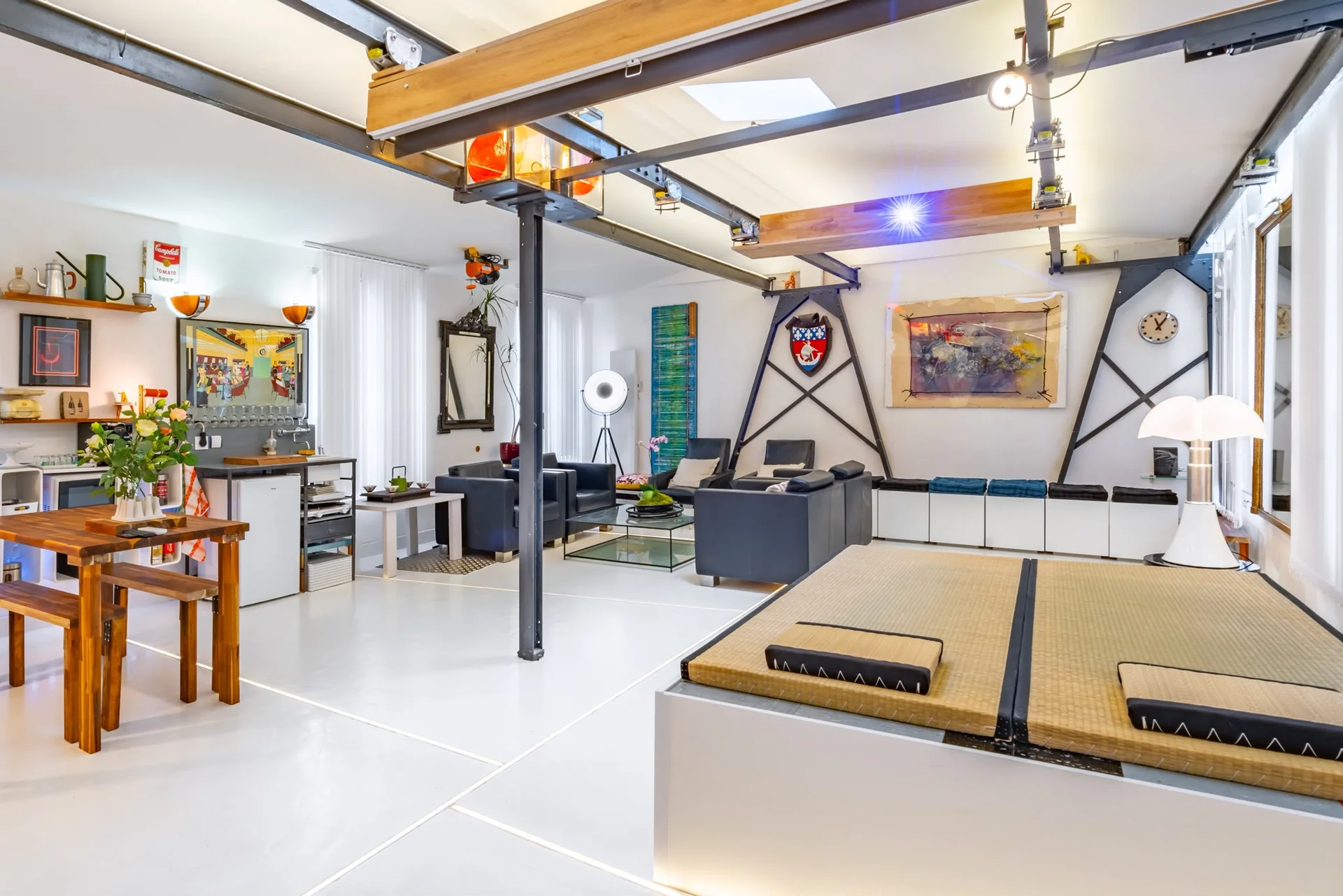 Vue large du loft atypique à Paris avec espace lounge, table en bois et plateforme modulable