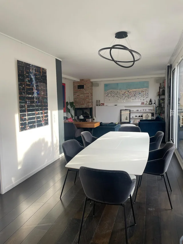Salle de réunion lumineuse avec table blanche, chaises noires, parquet foncé et vue panoramique sur Paris