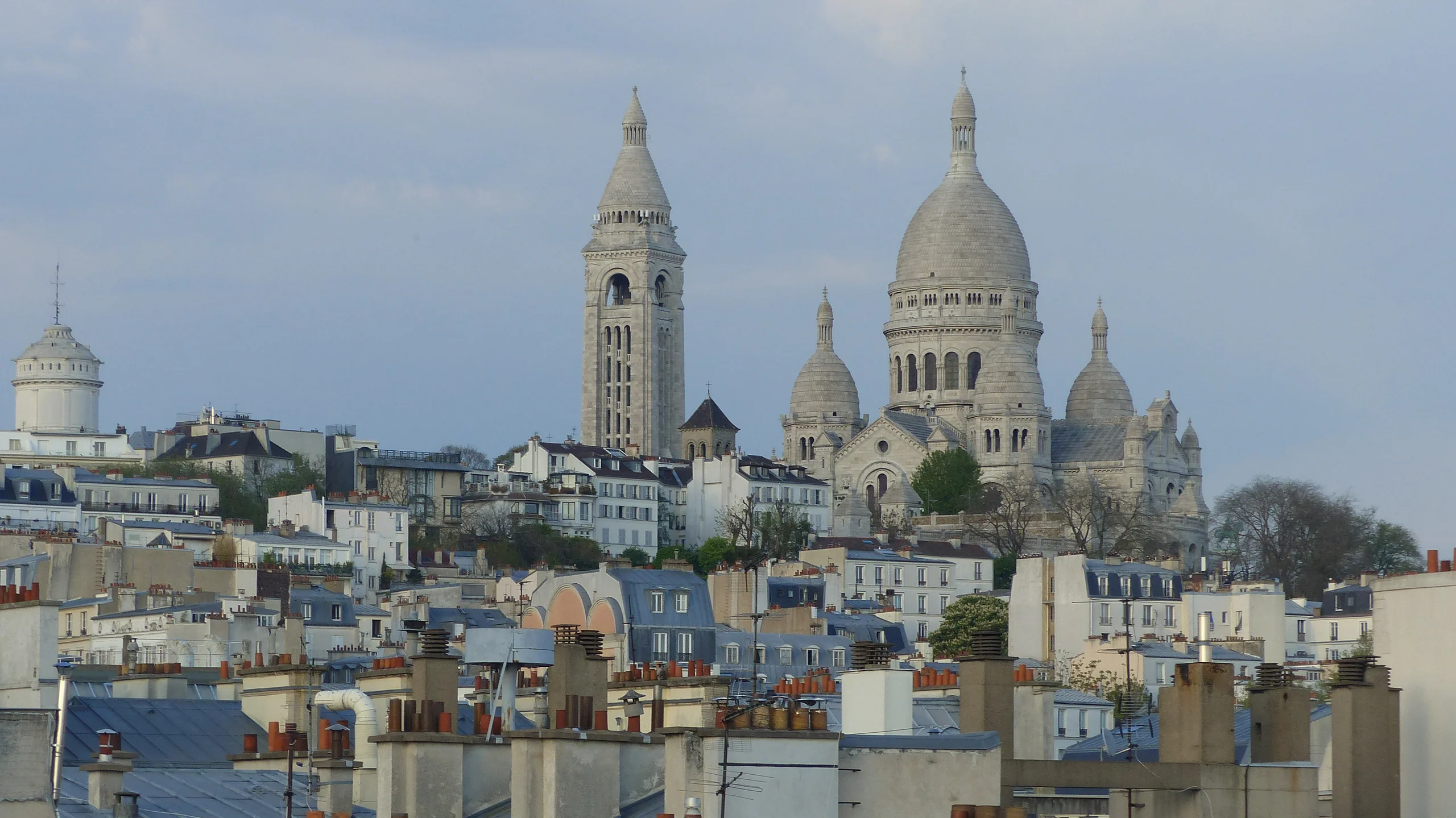 Rooftop parisien avec vue panoramique sur la Basilique du Sacré-Cœur et les toits de Montmartre sous ciel dégagé