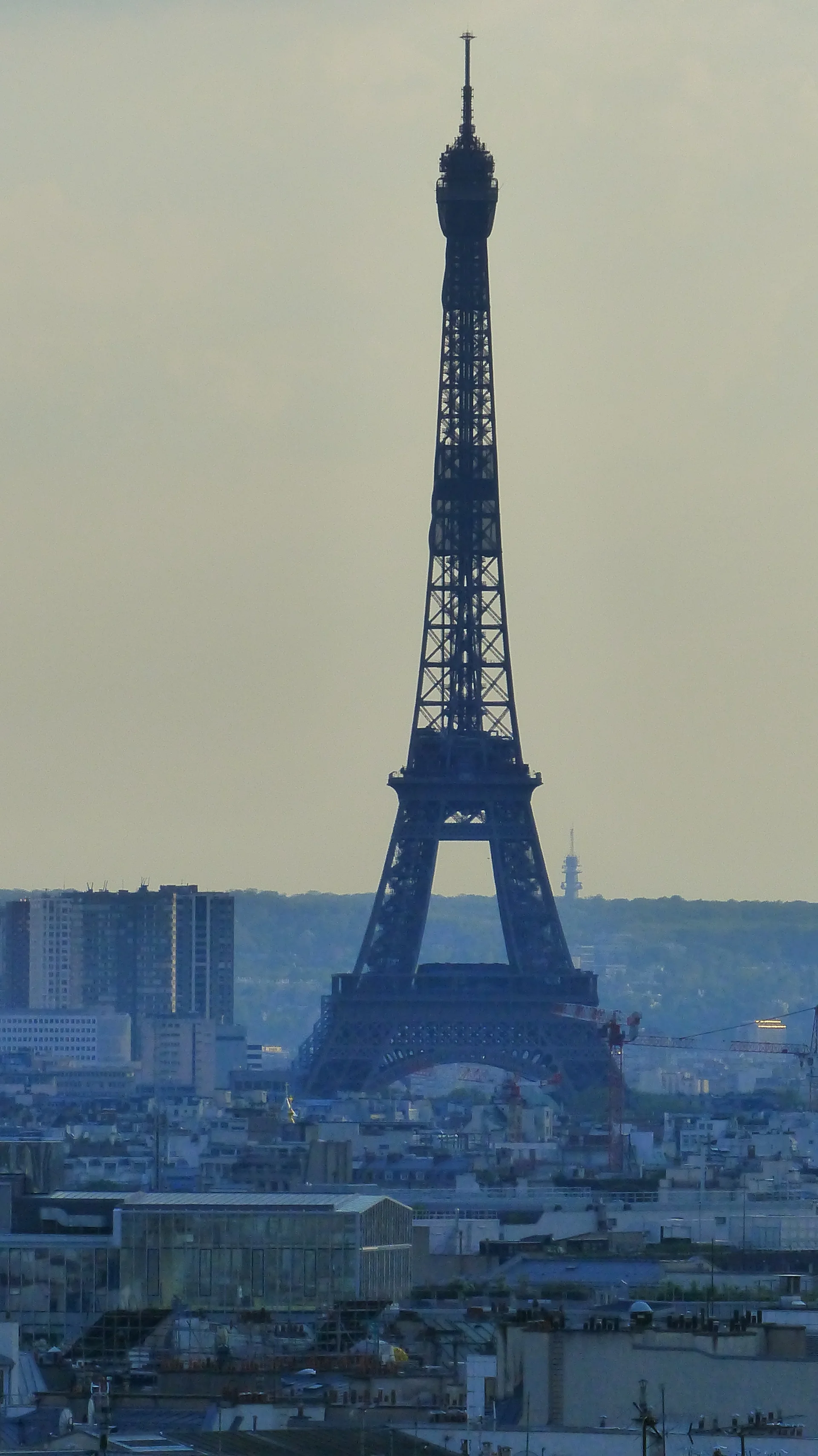 Tour Eiffel en silhouette au-dessus de l'horizon urbain parisien depuis une terrasse en hauteur