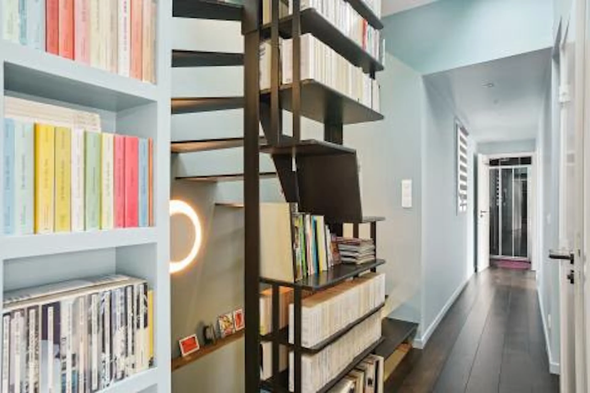 Couloir intérieur avec étagères blanches, structure bois foncé, néon rose, murs bleu pâle et sol gris