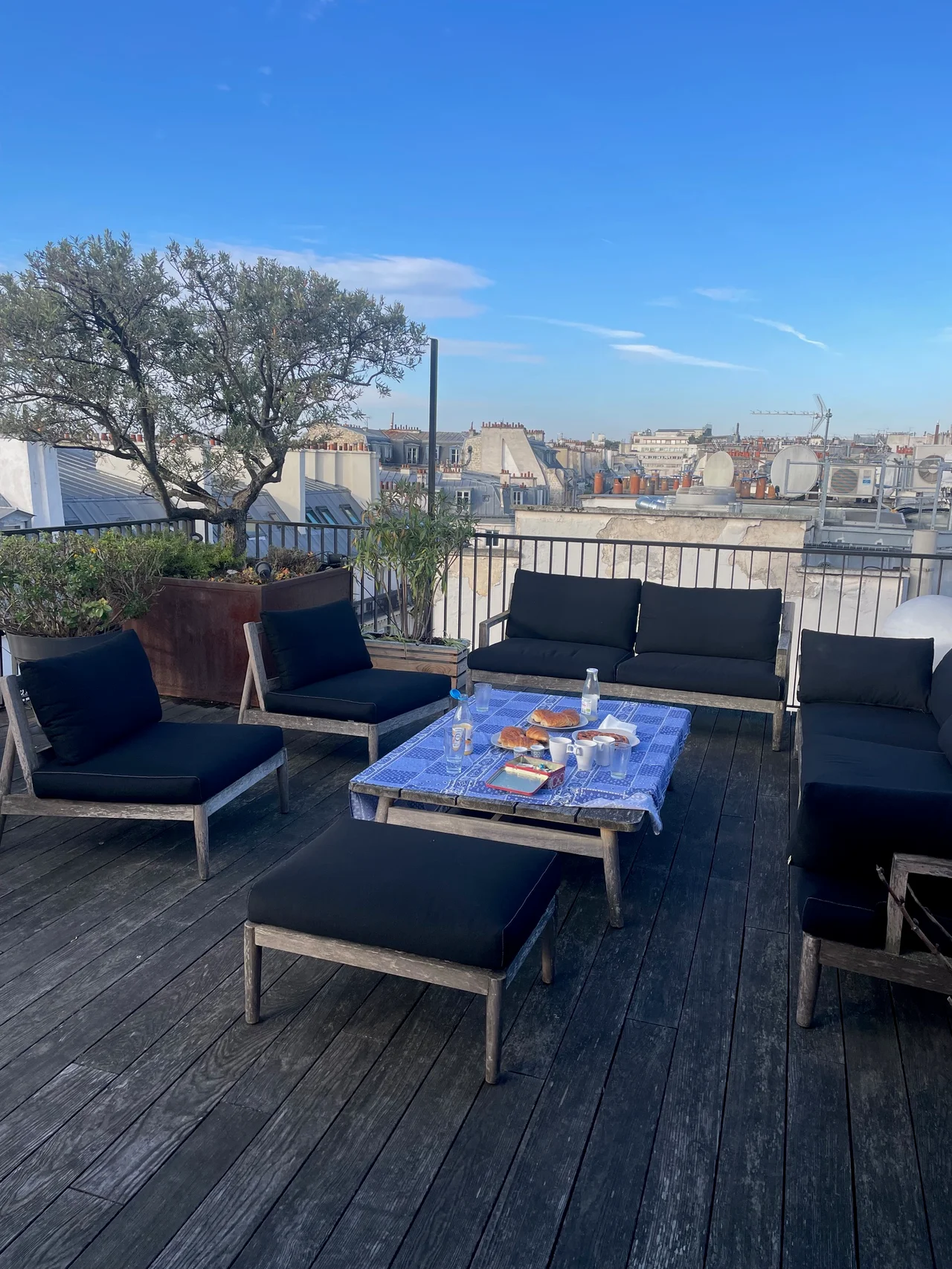 Terrasse panoramique avec mobilier design, vue dégagée sur toits parisiens et monument métallique sous ciel bleu