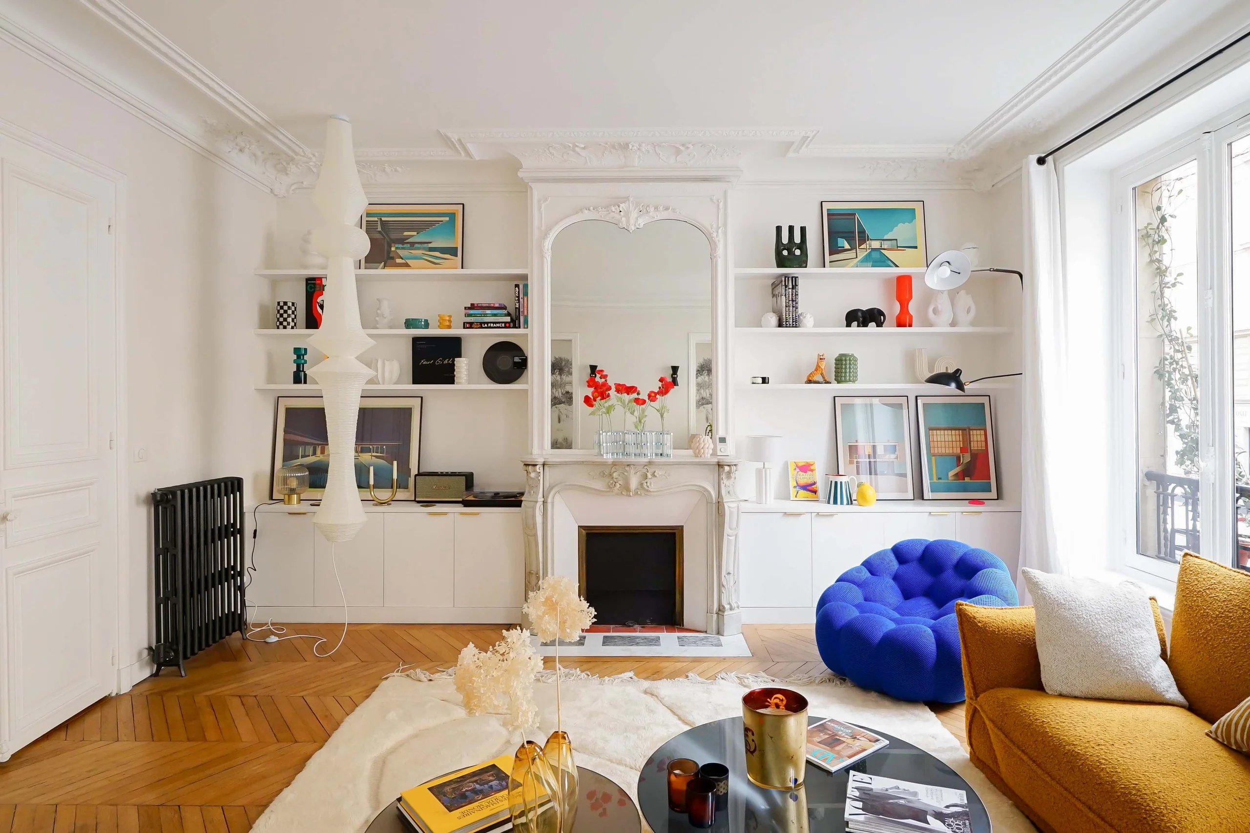 Salon haussmannien avec parquet chevron, cheminée blanche, rangements intégrés et mobilier jaune moutarde