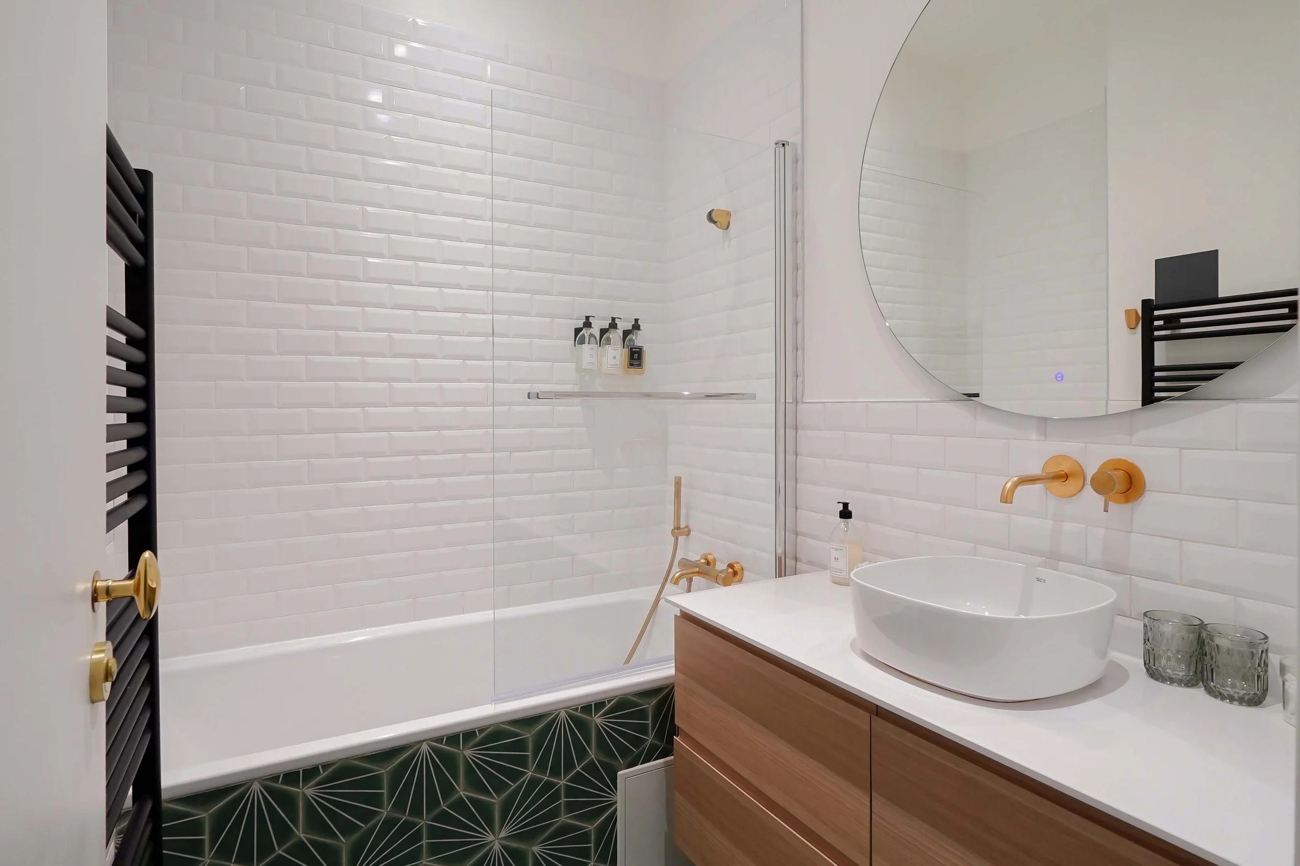 Salle de bain haussmannienne avec carrelage blanc métro, baignoire en alcôve, vasque ronde blanche et mobilier bois clair