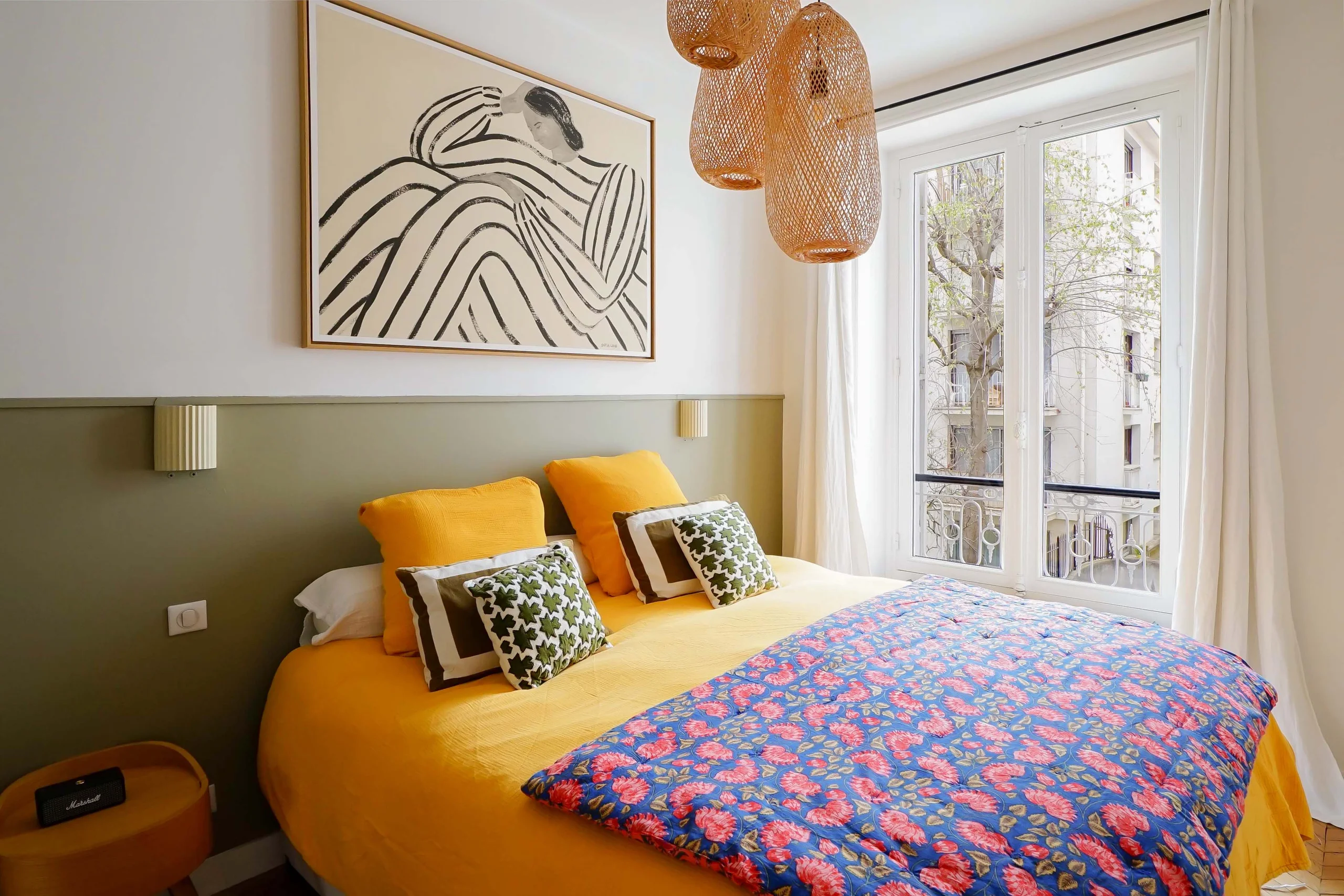 Chambre haussmannienne avec mur demi-peint vert olive, lit jaune vif, parquet clair et portes-fenêtres donnant sur le Luxembourg