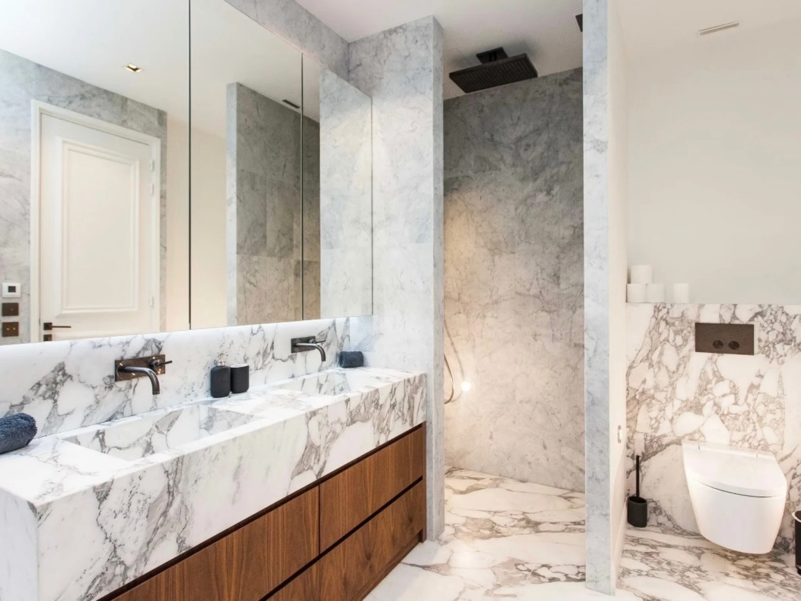 Salle de bains spacieuse avec vasque en marbre blanc, meuble bois, parois vitrées et carrelage marbre gris clair